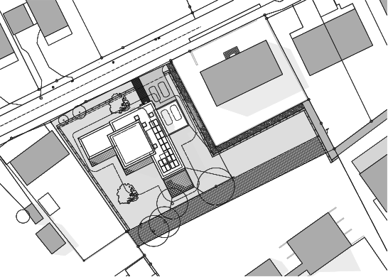 La maison et le garage vus d’en haut sur leur parcelle, avec les terrasses dallées, le jardin, les arbres, la route et les bâtiments voisins